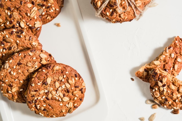 Top view of homemade oatmeal cookies with flax and sesame seeds on a white table. Healthy fitness food concept. Milk and biscuits, healthy breakfast food. Layout of Christmas cookies on a plate