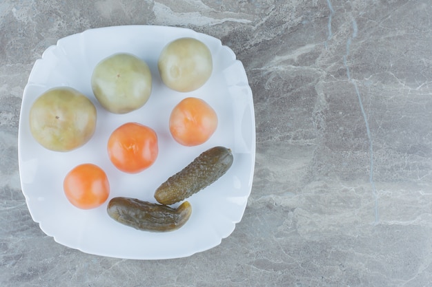 Free photo top view of homemade pickle. unripe tomatoes and cucumber on white plate.