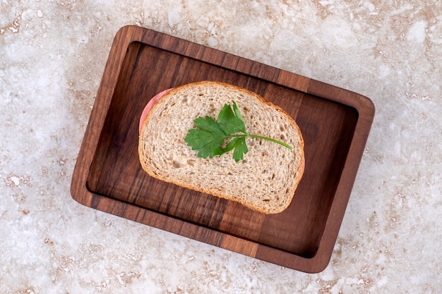 Foto gratuita vista dall'alto del panino con salame fatto in casa sul piatto di legno.