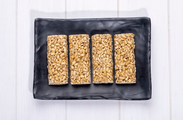 Free photo top view of honey bars with sunflower seeds on a black platter on rustic