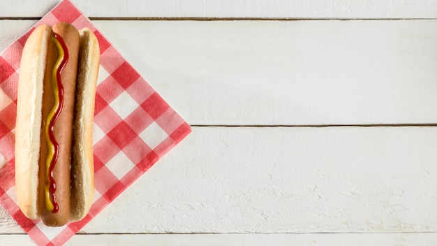 Free photo top view hot dog with napkin on wooden background