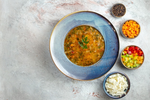 Zuppa di verdure calda vista dall'alto all'interno del piatto su uno spazio bianco-chiaro