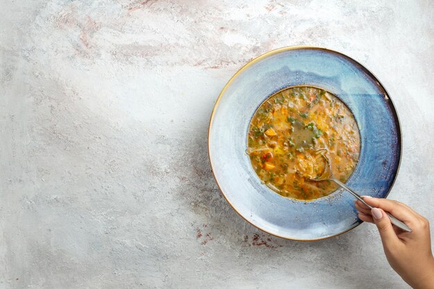 Вид сверху горячий овощной суп внутри тарелки на белом столе