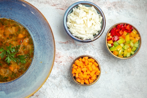 Вид сверху горячий овощной суп с нарезанными овощами на белом пространстве