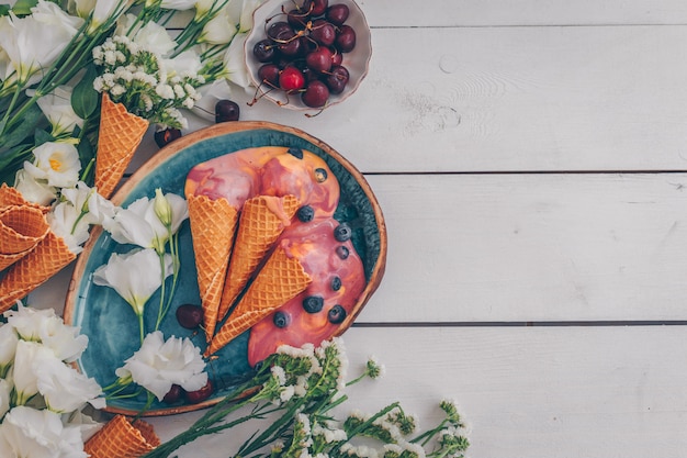 Top view ice cream in blue plate with flowers and fruit on white wood