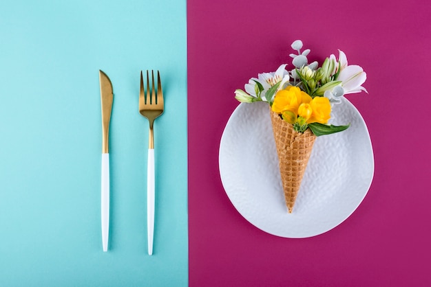 Top view ice cream cone with flowers and cutlery