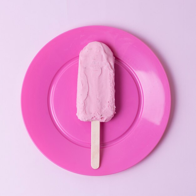 Вид сверху мороженое на палочке и розовой тарелке