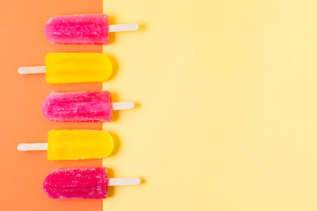 Free photo top view ice cream on sticks with flavor