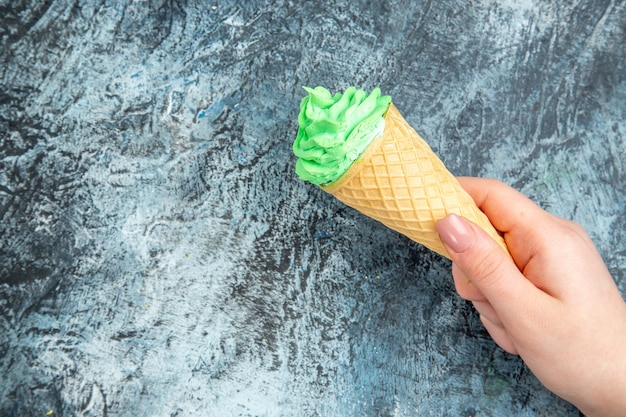 Вид сверху мороженого в руке женщины на темной поверхности