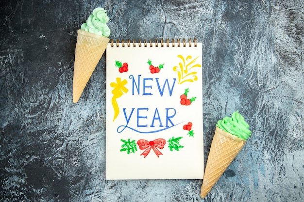 Free photo top view ice creams new year written on notebook on grey background