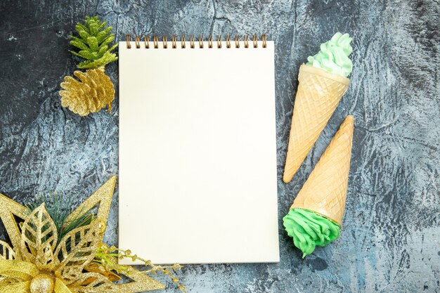 Top view ice creams and a notebook xmas ornament on grey background