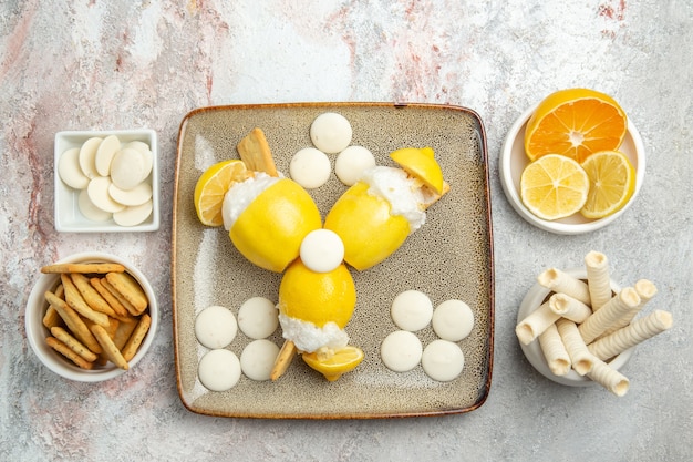 Top view iced lemons with candies and crackers on white table 