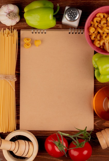 Top view of ingredients around note pad on wooden surface with copy space