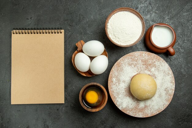 Top view ingredients for dough milk eggs and flour on grey space