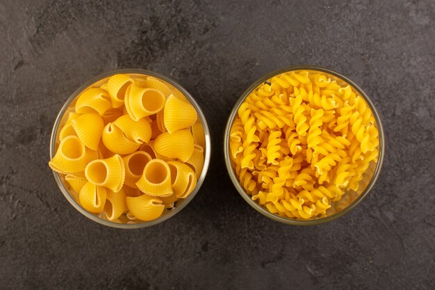 A top view italian dry pasta yellow raw inside bowls isolated on the dark