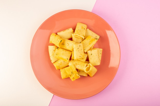A top view italian pasta with dried green herbs inside pink plate on white