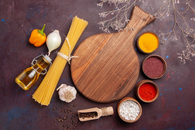 Top view italian pasta with seasonings on dark space