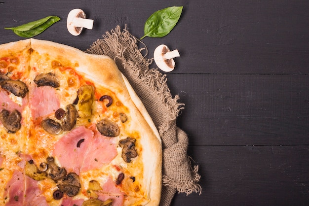 Вид сверху итальянской пиццы с грибами и базиликом на деревянный стол