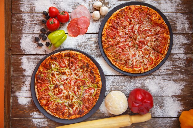 Top view of italian pizzas with tomato sauce, cheese and bell peppers