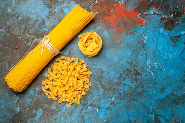 Top view of Italian various pastas for dinner preparation on the right side on blue background