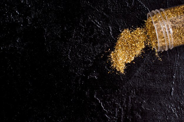 Top view jar with golden glitter on slate background