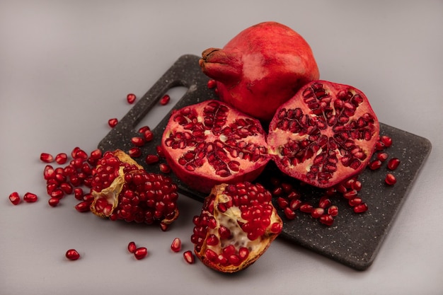 Top view of juicy halved and whole pomegranates on a black kitchen board