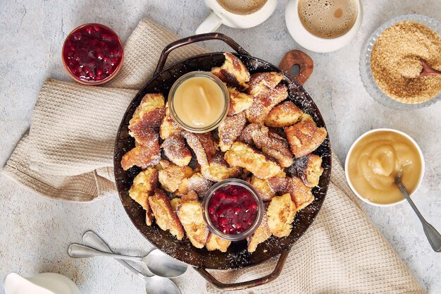 Top view of kaiserschmarrn with torn pancakes cranberries jam and apple puree on a table