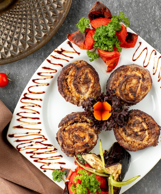 Top view of kebab roulette decorated with vegetables