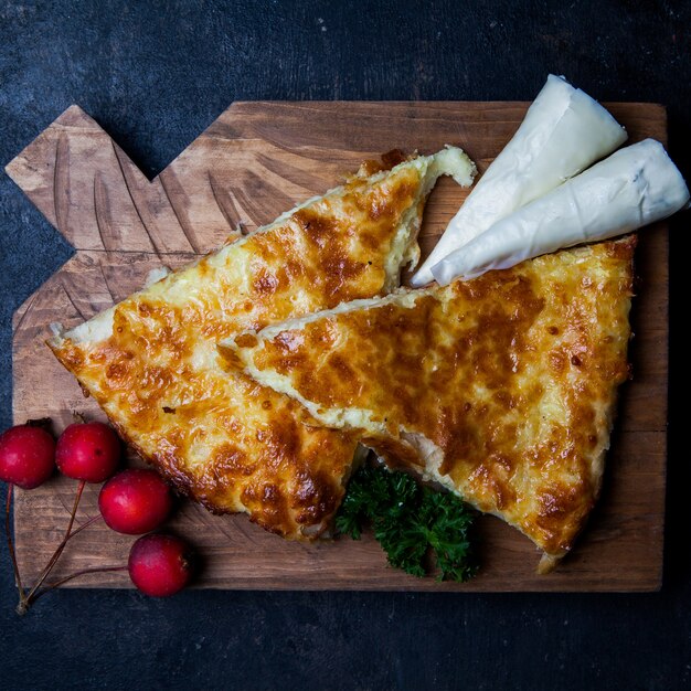 Top view khachapuri with nadugi and paradise apples and greens in cutting board