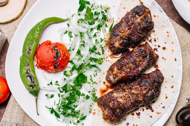 Top view khan kebab on pita bread with tomato and grilled pepper with onions and herbs