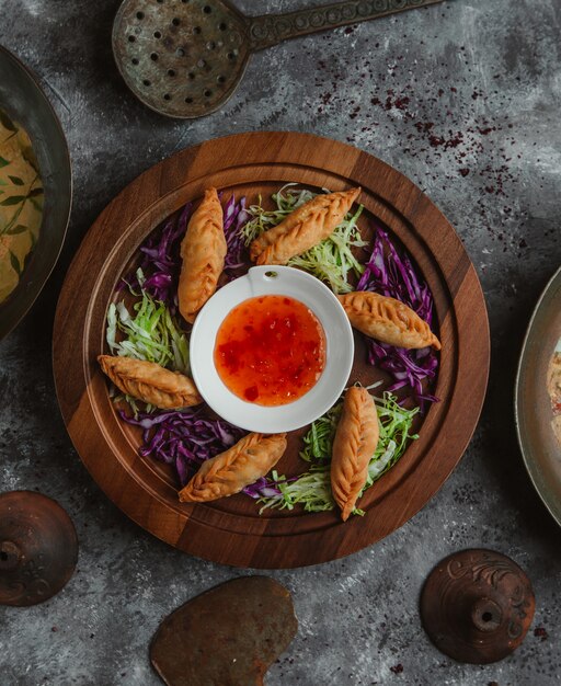 Top view khinkali roasted and served with herbs and chili sauce.