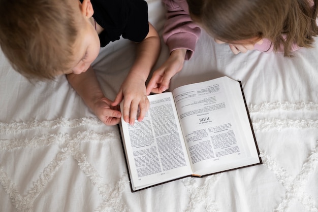 Foto gratuita bambini con vista dall'alto che leggono insieme la bibbia