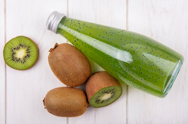 Top view kiwi with juice bottle on white wall