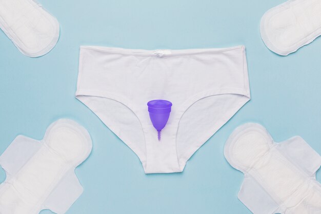 Вид сверху трусики с менструальной чашкой и гигиеническими прокладками