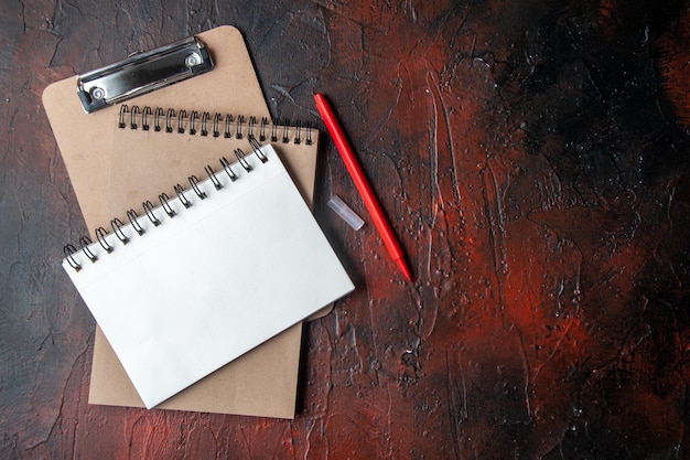 Top view of kraft spiral notebooks with pen on dark background