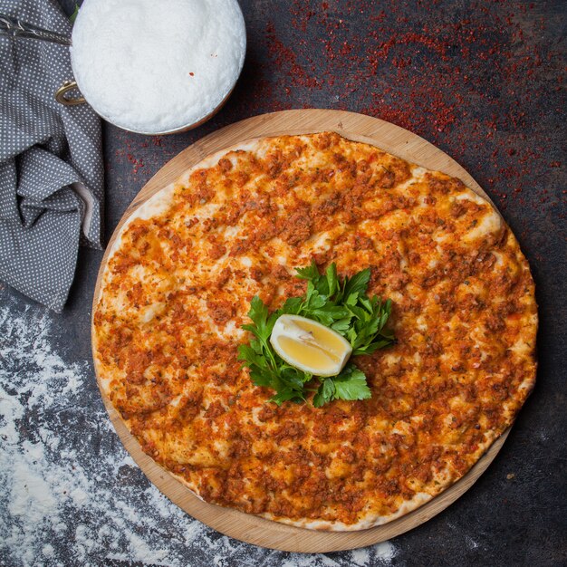 Top view lahmacun with parsley and lemon and ayran and rag in wooden food tray