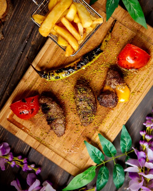 Top view of lamb kebab stuffed with cheddar served with french fries grilled vegetables