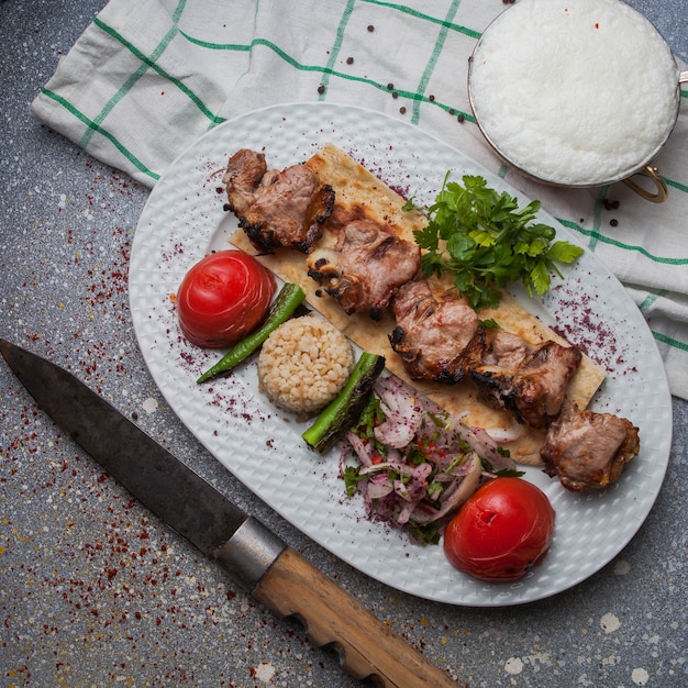 揚げ野菜と玉ねぎのみじん切りとアイランと白い皿にナイフと上面図ラムケバブ