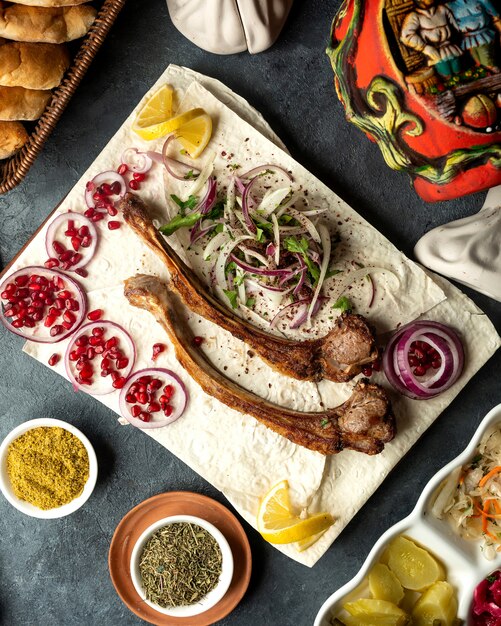 Top view of lamb ribs kebab with herbs onion and pomegranate beans on lavash