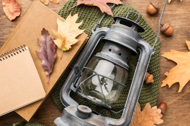 Top view of lantern with autumn leaves and notebook