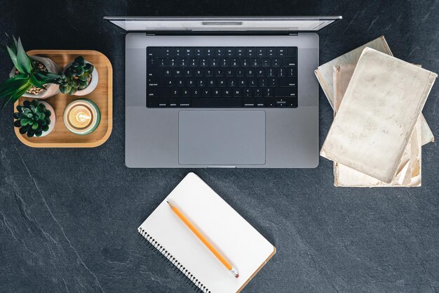 Top view laptop notebook and books on a dark background