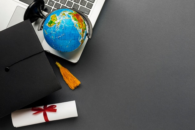 Top view of laptop with diploma and globe