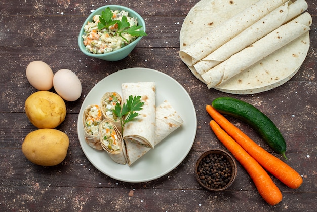 Top view lavash sandwich rolls sliced with salad and meat inside along with mayyonaise salad on the wooden desk snack food meal sandwich