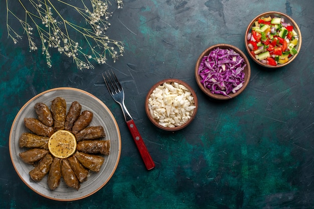 Foto gratuita vista dall'alto foglia dolma delizioso pasto di carne orientale arrotolato all'interno di foglie verdi sulla scrivania blu carne cibo cena piatto verdure salute