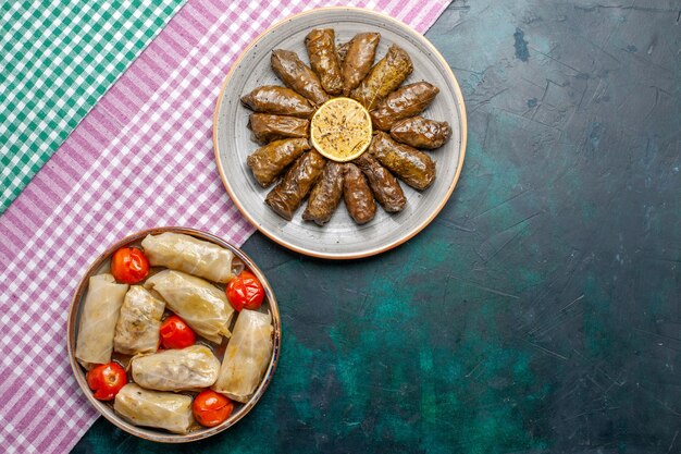 Top view leaf dolma eastern meat meal rolled inside green leaves with cabbage dolma on blue desk meat dinner dish east meal calorie