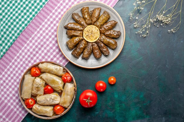 Вид сверху листовой долмы восточная мясная еда в зеленых листьях с капустной долмой на синем столе мясное обеденное блюдо восточная еда калории