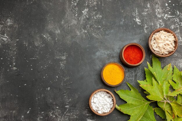 Top view of leaves and herbs on the bottom right side on dark grey table