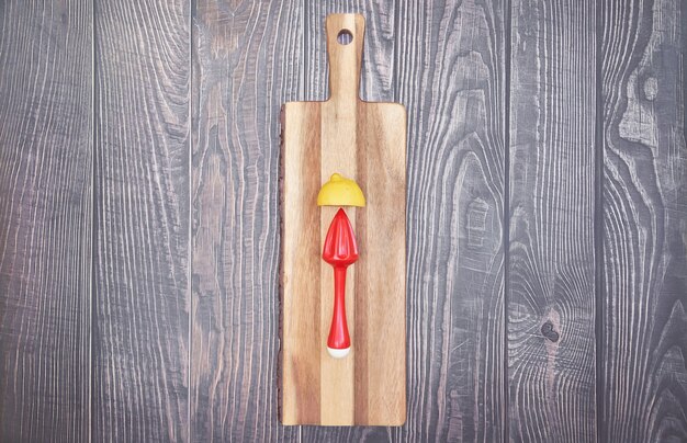 Top view of lemon and lemon squeezer on wooden board