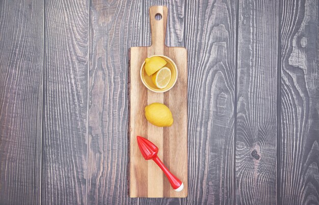 Top view of lemon and lemon squeezer on wooden board