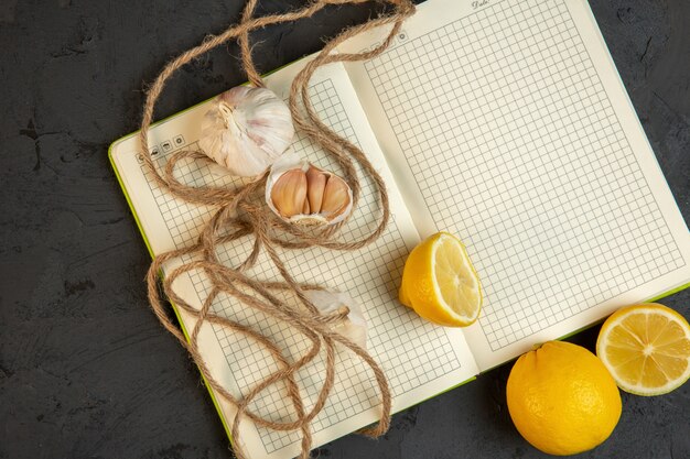 Top view of lemon slices and garlic on open empty notebook on grey